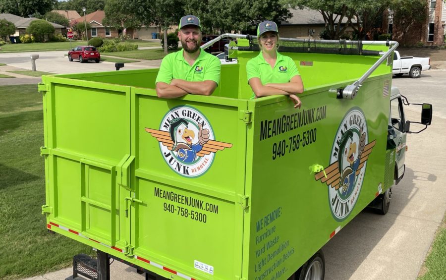 mean green team standing inside of junk removal truck before demolition services