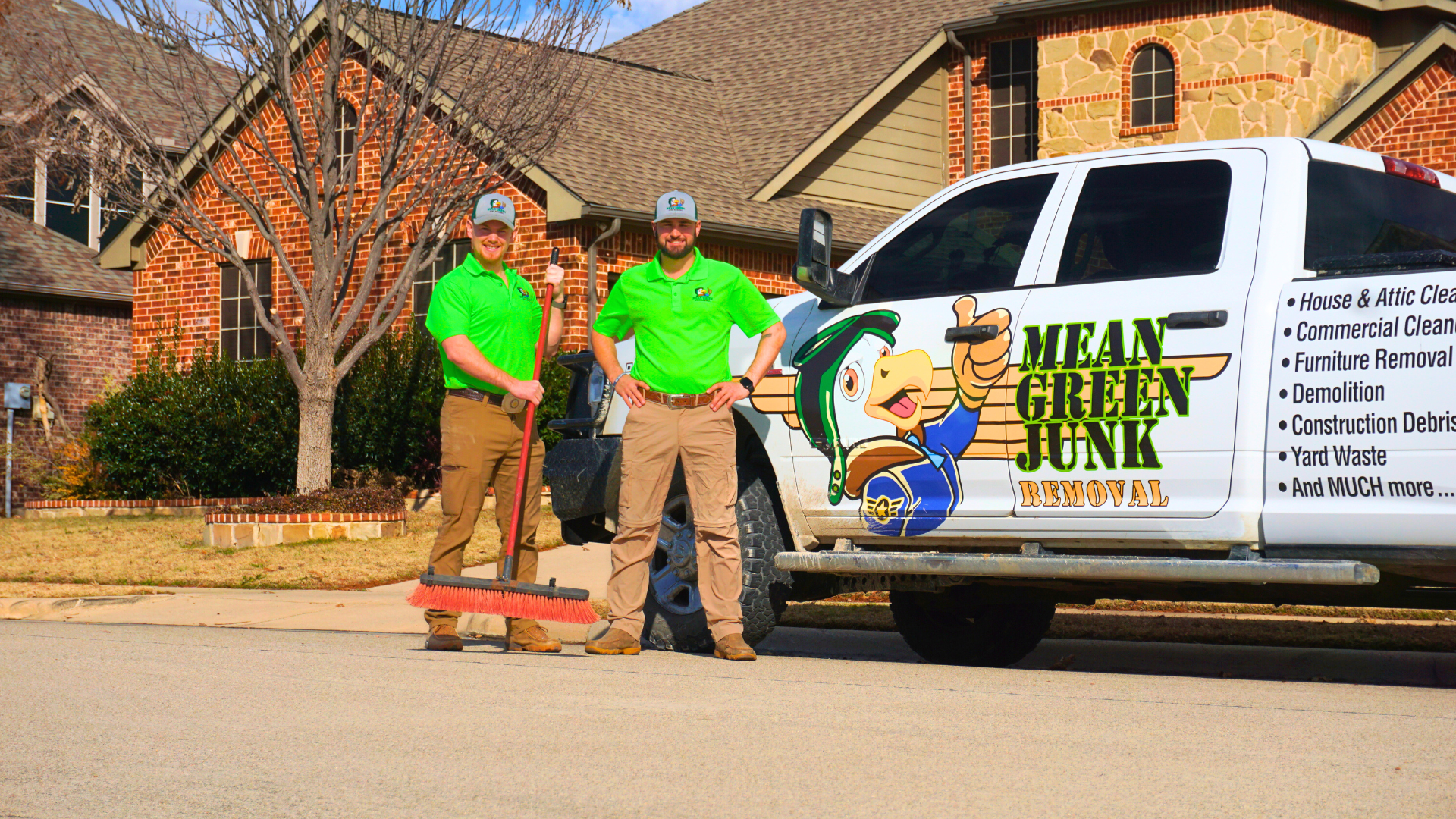 Mean Green Junk Removal team standing beside a branded truck during a residential junk removal service.